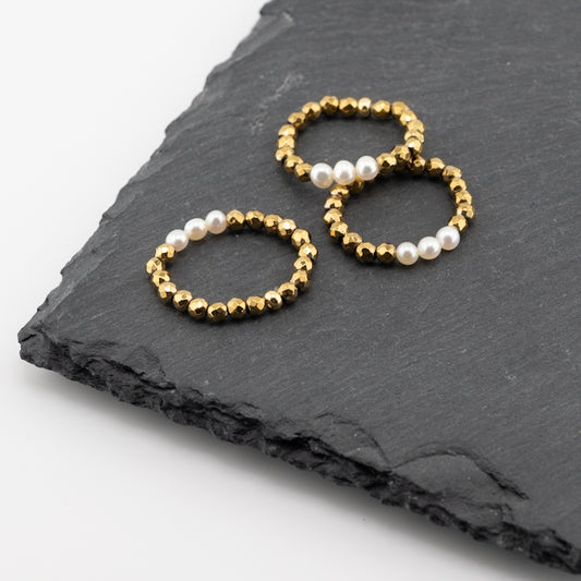 Drei Ringe aus facettierten, golden Kugeln und weißen Perlen.