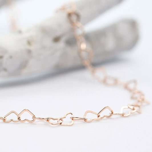 Detailaufnahme von rotgoldenem Armband aus kleinen Herzen.